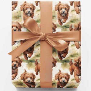 May include: A square gift box wrapped in paper featuring a repeating pattern of brown, fluffy puppies running through a grassy field. The box is tied with a smooth, solid light brown satin ribbon that is knotted in a bow at the center.