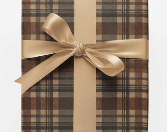 May include: A rectangular gift box wrapped in brown, tan, and dark gray plaid paper. The package is tied with a smooth, solid light tan satin ribbon that forms a decorative bow centered horizontally across the front of the wrapped box.