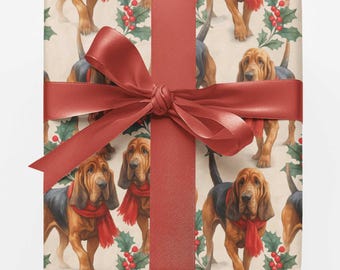 May include: A square gift box wrapped in cream-colored paper featuring a repeating pattern of brown and black bloodhound dogs wearing red scarves, interspersed with green holly leaves and red berries, tied with a wide red satin ribbon bow.