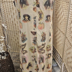 Pode incluir: Um vestido comprido sem mangas em tecido bege claro com uma estampa vintage repetida de cavalos, borboletas, pêssegos e retratos. O vestido tem um fecho frontal de botões e um colarinho largo decorado com renda verde clara.