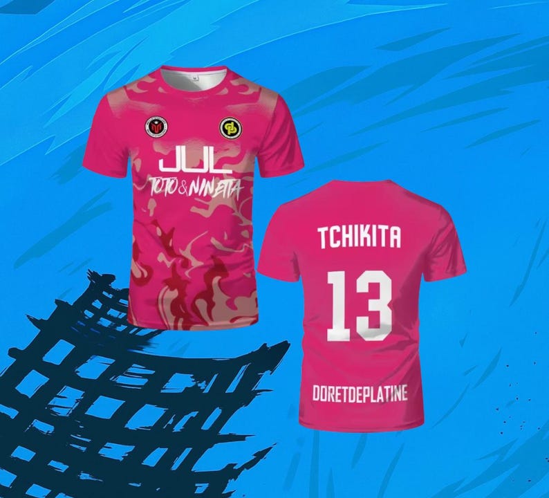 May include: A short-sleeved pink t-shirt featuring a camouflage pattern, the text JUL and TOTO & NINETTA on the front, and the text TCHIKITA, the number 13, and DORETDEPLATINE on the back, displayed from both front and rear perspectives.