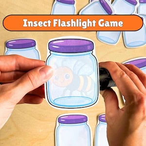 Könnte beinhalten: Ein Papierausschnitt eines Glasgefäßes mit violettem Deckel, das eine gezeichnete Biene enthält, mit dem Text Insect Flashlight Game darüber. Das Glas wird vor einem hellen Hintergrund gehalten, umgeben von weiteren ähnlichen Ausschnitten.