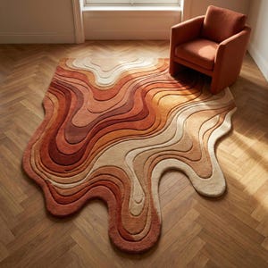 May include: A large area rug featuring an irregular, organic shape with flowing, wavy lines in a gradient of warm colors including deep rust, burnt orange, terracotta, tan, and cream. The rug has a thick, textured pile and a soft, plush appearance.