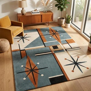 May include: A rectangular area rug featuring a geometric pattern with blue, cream, and burnt orange blocks. The design includes black starburst motifs with circular accents, intersecting lines, and solid shapes arranged in a structured composition.