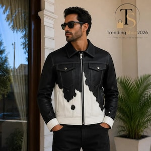 Może przedstawiać: Czarno-biała skórzana kurtka w łaty z pełnym srebrnym zamkiem błyskawicznym, spiczastym kołnierzem, dwiema kieszeniami na piersi ze srebrnymi zatrzaskami oraz długimi rękawami zakończonymi białymi mankietami o kontrastowym wzorze.