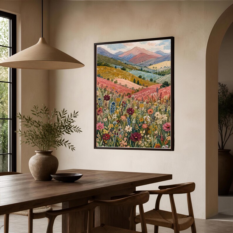 May include: A framed vertical wall art print featuring a landscape painting of a vibrant wildflower meadow in the foreground with rolling hills and distant mountains under a soft sky in shades of pink, blue, green, yellow, and deep red.