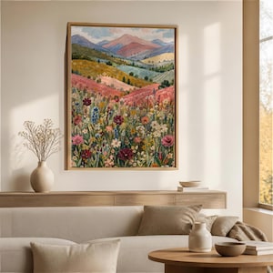 May include: A framed wall art print featuring a landscape painting of a vibrant wildflower meadow in the foreground with rolling hills and distant mountains in the background. The scene displays a palette of pink, green, blue, and yellow tones.