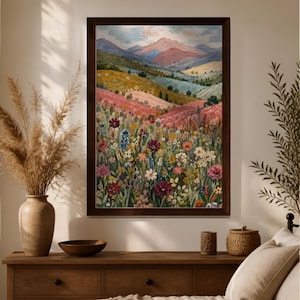 May include: A framed landscape painting featuring a vibrant wildflower meadow in the foreground with rolling hills and distant mountains under a soft sky. The artwork displays a rich palette of pink, yellow, green, and deep red floral tones.