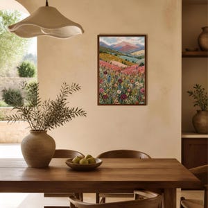 May include: A rectangular framed wall art print featuring a landscape painting of a vibrant wildflower meadow in the foreground with rolling hills and distant mountains under a soft sky in shades of pink, blue, green, and yellow.
