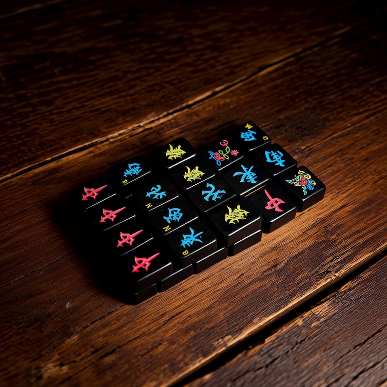 May include: A set of black rectangular tiles arranged in a grid, featuring colorful engraved symbols including Chinese characters, directional letters, and floral motifs in shades of red, blue, yellow, and pink, with a glossy finish on each piece.