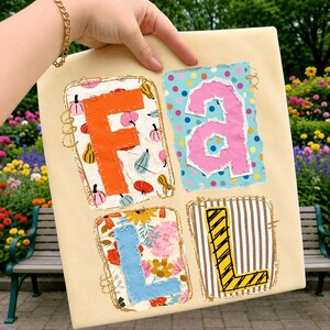 Op de afbeelding: Een vierkant crèmekleurig stoffen bord met het woord FALL, gespeld in vier afzonderlijke rechthoekige patches. Elke letter is aangebracht op een andere achtergrond met patronen, waaronder pompoenen, kleurrijke stippen, bloemen en bruine strepen.