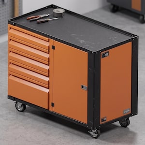 Puede incluir: Un armario de herramientas móvil de metal naranja y negro con cuatro cajones horizontales a la izquierda y una puerta vertical a la derecha. La superficie superior es negra y contiene unos alicates, un destornillador y cinta adhesiva.