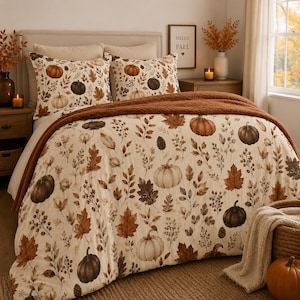 May include: A bedding set featuring a cream-colored comforter and two matching pillow shams decorated with a pattern of brown and orange pumpkins, autumn leaves, and pinecones, accented by a solid dark brown textured throw blanket.