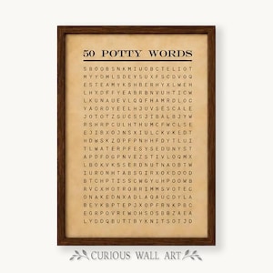 May include: A framed wall art print featuring a word search puzzle titled 50 POTTY WORDS. The print has a beige, parchment-like background with black text and a dark brown wooden frame. The grid contains various letters arranged in rows.