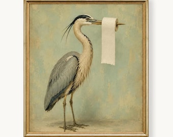 May include: A framed wall art print featuring a grey heron standing in profile against a muted light blue background. The bird holds a roll of white toilet paper on its long, pointed beak. The artwork is enclosed in a thin gold-toned frame.