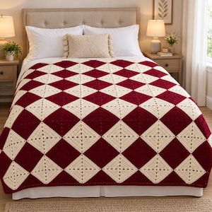 May include: A handmade crochet blanket featuring a repeating diamond pattern in alternating deep burgundy and cream colours. The textile is constructed from individual square motifs joined together to create a large, geometric, textured bed covering.