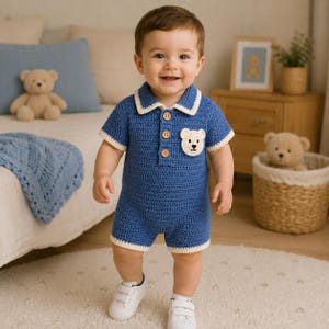 May include: A blue crochet romper featuring a collared neckline, three wooden buttons, and a small white bear applique on the chest. The garment has short sleeves and short legs, both finished with a cream-colored trim along the edges.