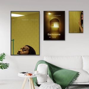 May include: Three framed posters featuring the Backrooms movie title and release date 5.29.26. The left poster shows a person looking up in a yellow room. The centre poster depicts a dark arched doorway. The right poster shows a person touching a wall.