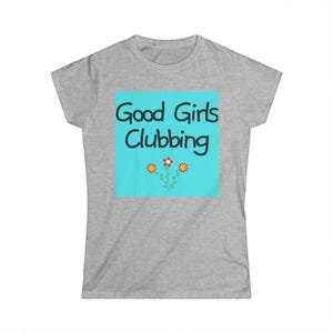 May include: A heather grey short-sleeve t-shirt featuring a central light blue square graphic. The text "Good Girls Clubbing" is printed in black, rounded lettering above three small, stylised flowers with orange and red petals.