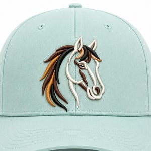 May include: A light mint green baseball cap featuring a detailed embroidered horse head on the front panel. The horse design is rendered in shades of cream, tan, brown, and black, showcasing a flowing mane and a defined profile view of the animal.
