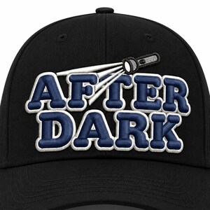 May include: A black baseball cap featuring an embroidered design of a flashlight emitting a white beam of light above the text AFTER DARK in bold, navy blue, block-style letters with a white outline, centered on the front of the cap.