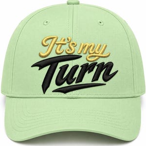 May include: A light green baseball cap featuring embroidered text on the front. The words It's my are stitched in a gold script font, while the word Turn is stitched below in a bold black font with a stylised underline design.
