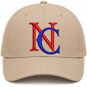 Op de afbeelding: Een beige honkbalpet met een geborduurd logo op de voorzijde. Het logo bestaat uit een grote rode letter N die overlapt met een blauwe letter C. De pet heeft een gestructureerde kroon, een gebogen klep en gestikte oogjes voor ventilatie.