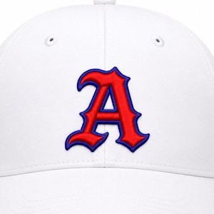 May include: A white baseball cap featuring a prominent embroidered letter A in red with a dark blue outline centered on the front panel. The cap has a structured crown, a curved brim, and small ventilation eyelets on the upper panels.