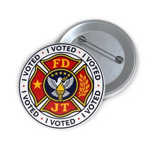 Puede incluir: Una chapa redonda con un emblema de bomberos en rojo y oro que muestra una paloma y una antorcha en el centro. El texto I VOTED se repite en el borde blanco. El diseño incluye una estrella amarilla y una rama de laurel dorada.