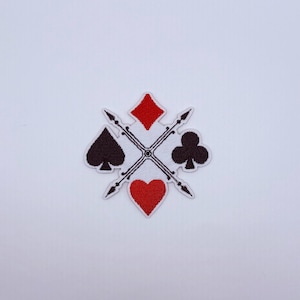 May include: An embroidered patch featuring the four playing card suits arranged in a cross pattern. A red diamond is at the top, a red heart at the bottom, a black spade on the left, and a black club on the right, all centered over two crossed arrows.