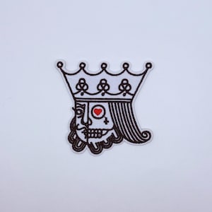 May include: An embroidered patch featuring a split-face design of a king playing card character. One side shows a human profile with a mustache, while the other side depicts a skull with a red heart symbol in the eye socket, topped by a crown.