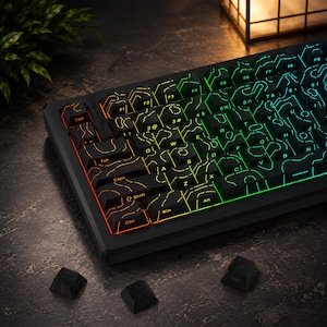 Könnte beinhalten: Eine schwarze mechanische Tastatur mit individuellen Tastenkappen, die ein topografisches Linienmuster aufweisen. Die Tasten sind mit einer RGB-Hintergrundbeleuchtung versehen, die von Rot links zu Grün und Blau rechts verläuft. Drei lose Tasten liegen daneben.
