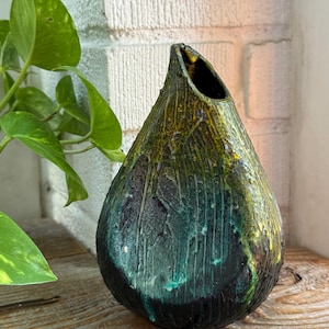 Peut inclure: Un vase en céramique en forme de goutte d'eau avec une base noire texturée qui se transforme en glaçures turquoise et jaune vives. La surface présente des motifs de coulures verticales et une finition rugueuse avec une ouverture étroite.