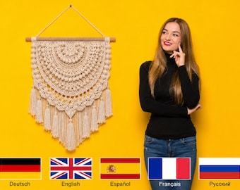 May include: A cream-colored macrame wall hanging featuring intricate knotted patterns, a semi-circular design with textured bobbles, and a bottom edge finished with long, flowing fringe. The piece is suspended from a wooden dowel with a cord.