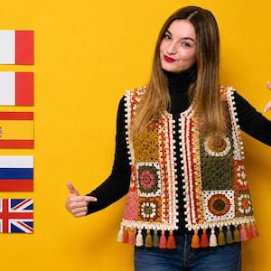 May include: A sleeveless crochet vest constructed from multicolored square patches in shades of olive green, mustard yellow, brown, and cream. The garment features a cream-colored pom-pom trim along the front edges and a row of small tassels at the hem.