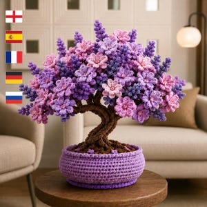 May include: A crochet bonsai tree featuring a twisted brown trunk and a dense canopy of purple and light pink flowers. The tree is potted in a round, textured purple crochet base. The entire structure is crafted from yarn with visible stitches.