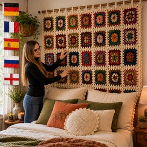 May include: A large rectangular crochet wall hanging featuring a grid of multicolored granny squares joined by cream-colored yarn. The textile is suspended from a wooden rod above a bed with various pillows in shades of olive, orange, and cream.