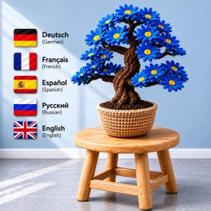 May include: A crocheted bonsai tree featuring a textured brown trunk and numerous bright blue daisy-like flowers with yellow centers. The tree is planted in a beige crocheted pot, which sits atop a small, light-colored wooden stool.