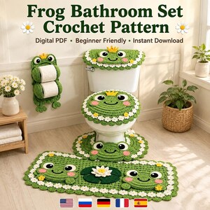 May include: A green crochet bathroom set featuring frog designs with yellow crowns, white daisy borders, and pink cheeks. The set includes a toilet tank cover, a toilet seat cover, a pedestal rug, a rectangular floor rug, and a wall-mounted toilet paper holder.