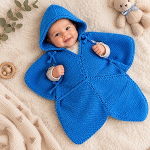 Könnte beinhalten: Ein leuchtend blauer, gestrickter Babyschlafsack mit Kapuze in Sternform. Das Kleidungsstück hat eine kraus rechts gestrickte Textur, dekorative Bindebänder an den Armöffnungen und eine Mittelnaht, die den Körper des Säuglings vollständig bedeckt.