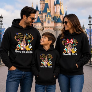 May include: Black hooded sweatshirts featuring a graphic of a castle inside a Mickey Mouse ear outline, surrounded by fireworks and cartoon characters. The text "Disney Trip 2026" is printed below the graphic in a white, stylized font.