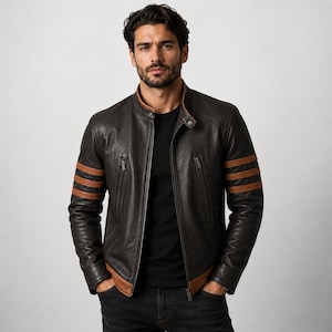 May include: A dark brown leather jacket featuring a stand-up collar, a full-length front zipper, and two vertical zippered chest pockets. The sleeves are accented with three horizontal tan stripes, and the hem is finished with a tan leather band.
