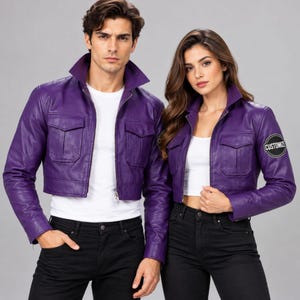 May include: Two matching purple cropped leather jackets with pointed collars, long sleeves, and two front chest pockets. The jacket on the right features a circular black patch on the left sleeve with the white text CUSTOMIZE printed inside.