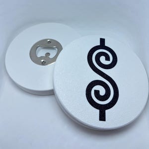 May include: Two circular white bottle openers. One opener displays a black stylized dollar sign symbol on its top surface. The other opener is flipped over to reveal the metallic silver-colored steel mechanism used for opening bottles.