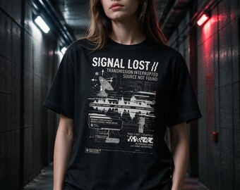 Może przedstawiać: Czarny t-shirt z krótkim rękawem z białym nadrukiem graficznym z tekstem SIGNAL LOST // TRANSMISSION INTERRUPTED SOURCE NOT FOUND. Wzór zawiera ikonę anteny satelitarnej, cyfrowe przebiegi falowe oraz techniczne napisy.
