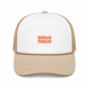 Może przedstawiać: Biało-beżowa czapka typu trucker z siateczkowym tyłem i pełnym przednim panelem. Na środku przedniego panelu znajduje się napis SUNDAY FUNDAY wyszyty pomarańczowymi literami. Beżowy sznurek biegnie poziomo wzdłuż podstawy przedniego panelu.