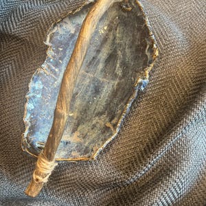 Handmade ceramic leaf dish with rich dark blue-gray glaze and natural wood accent
