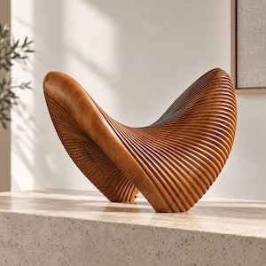 Può includere: Un oggetto scultoreo intagliato in legno marrone chiaro, caratterizzato da una forma curva a ala con profonde scanalature parallele su tutta la superficie, creando una texture ritmica e nervata che segue i contorni dell'oggetto.