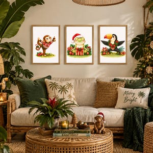 Puede incluir: Tres cuadros de pared con ilustraciones de un mono con suéter navideño, una rana con gorro de Papá Noel y un tucán con corona navideña. Los dibujos tienen fondo blanco y están en marcos de madera clara sobre la pared.