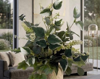 May include: A large artificial floral arrangement featuring variegated green and white leaves mixed with small cream-colored flower spikes. The foliage is displayed in a textured, beige, rounded ceramic vase with a porous, stone-like surface finish.
